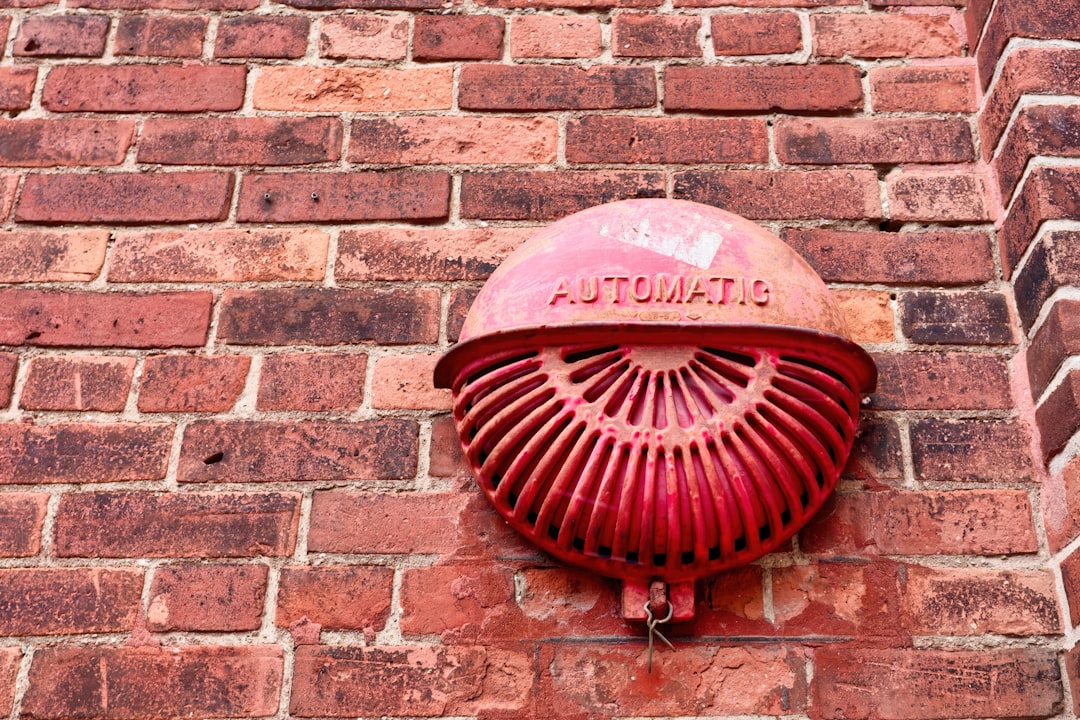 Red automatic alarm mounted on brick wall