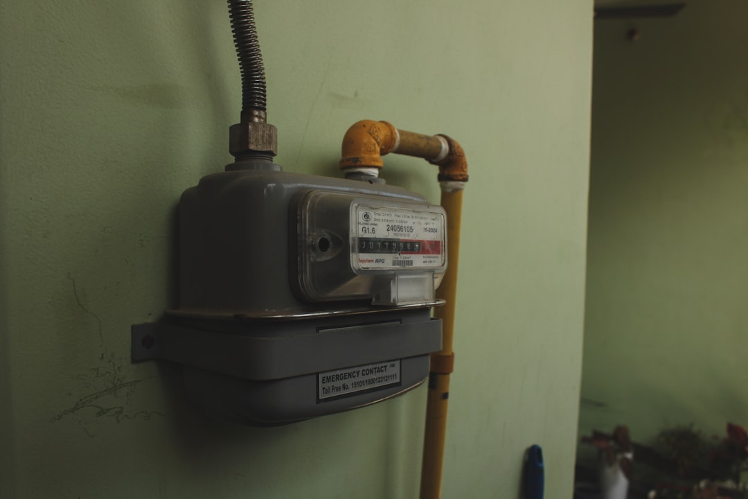 A gas meter mounted on a pale green wall.