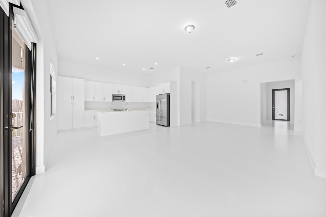 Modern white kitchen and living area with large windows.