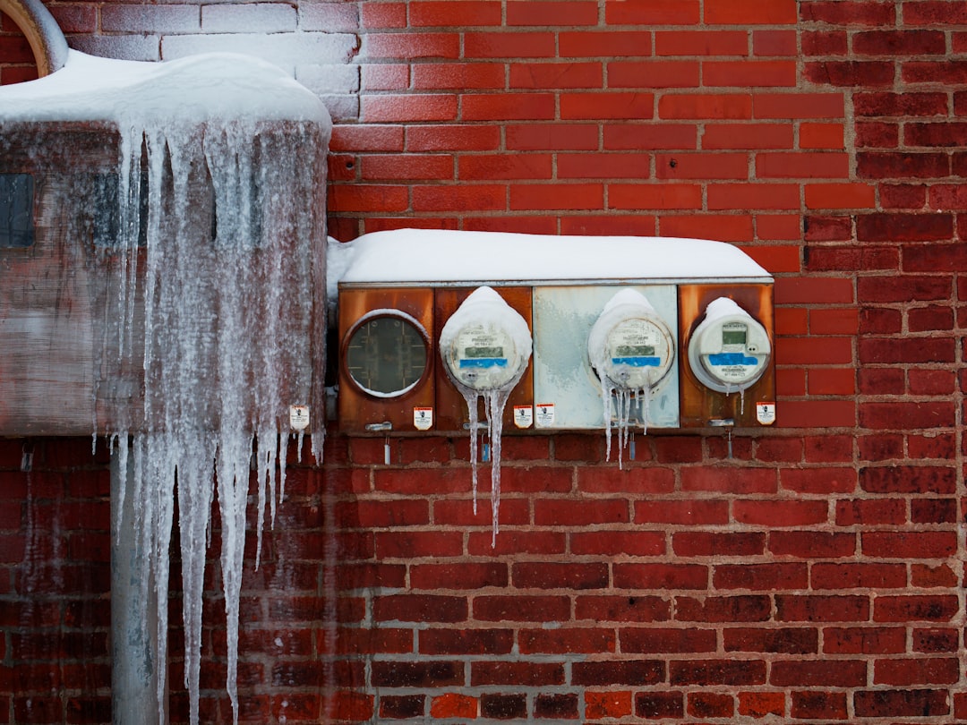 Icicles hang from frozen utility meters on brick wall